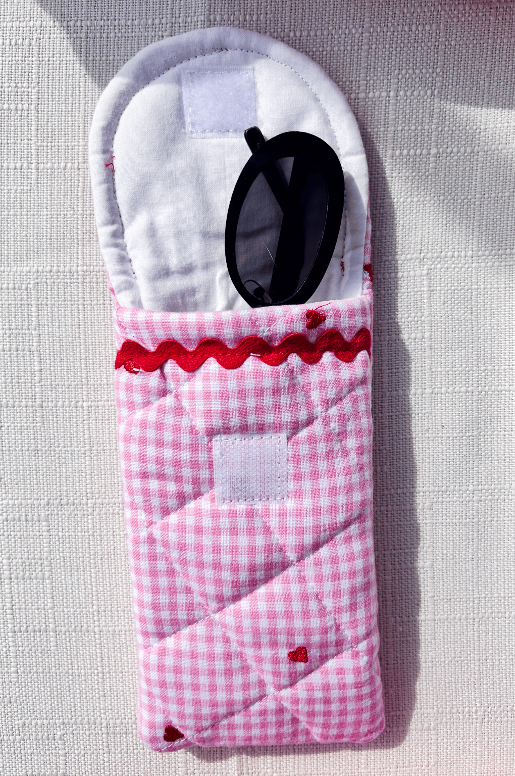 Handmade pink gingham quilted glasses case with embroidered red hearts and red rickrack trim perfect for valentines day or teachers day gift
