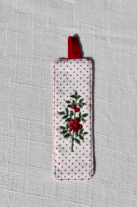 Handsewn white fabric bookmark with small red polka dots and an embroidered tomato plant on both sides, finished with a red fabric loop at the top. perfect for cookbooks