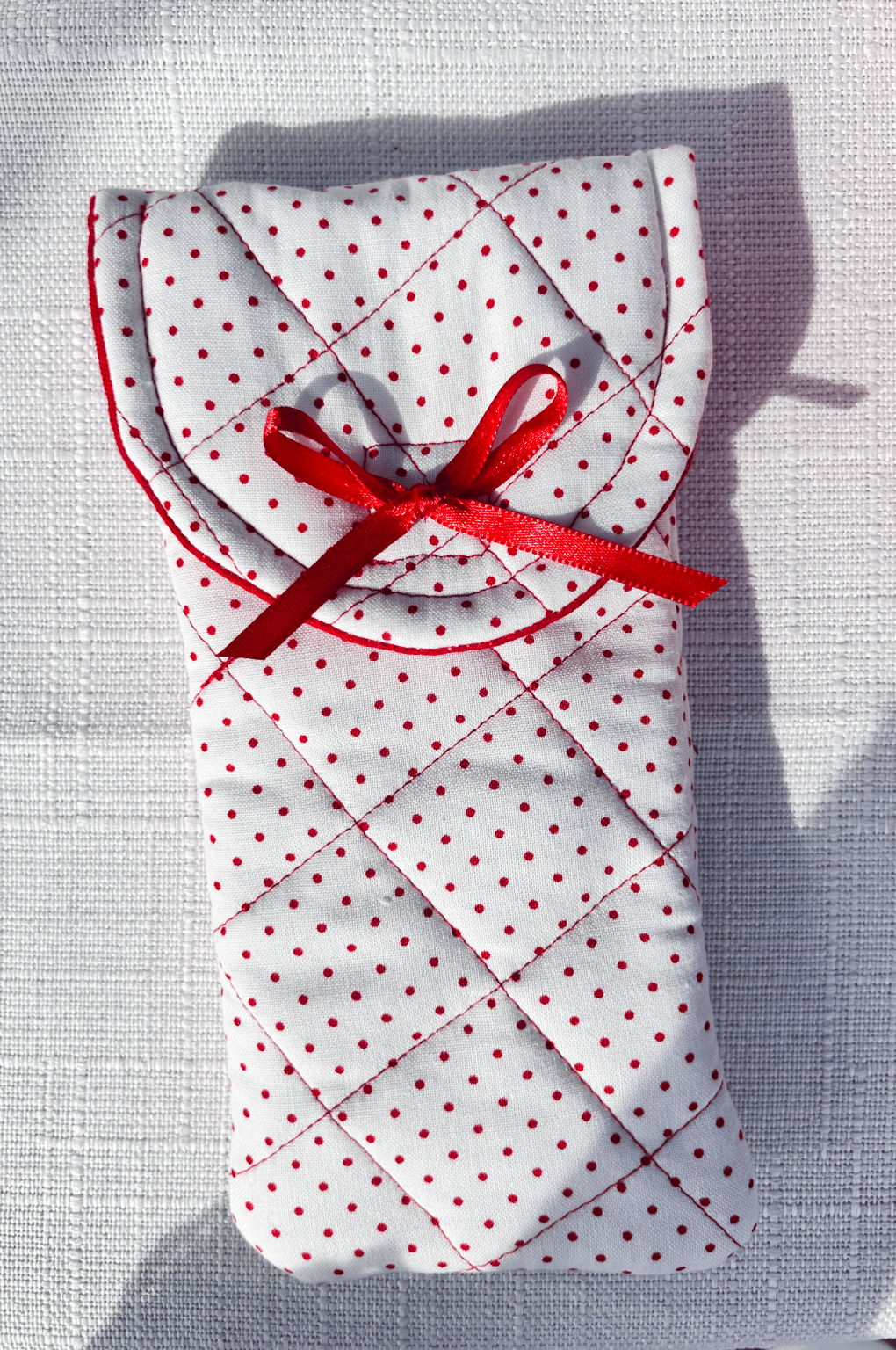 white and red Polka dot soft  handmade quilted glasses case with flap and hidden velcro closure and a red bow on the front, perfect for holding most standard size glasses